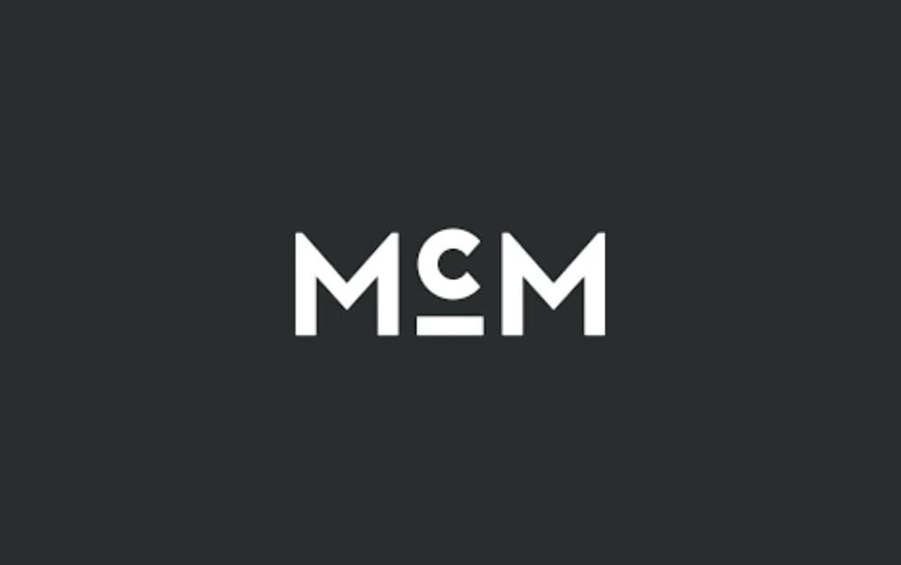 McMillan agency logo featuring bold white letters 'MCM' on a dark background.